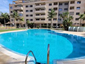 a large blue swimming pool in front of a building at LA MARINA in Torre del Mar