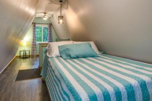 Schlafzimmer mit einem Bett mit blau-weiß gestreifter Bettwäsche in der Unterkunft A-Frame Cabin in Rocky Mount with Furnished Deck! in Rocky Mount