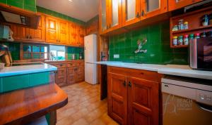 a large kitchen with wooden cabinets and green tiles at BFA - R149 Casa adosada Alorda con piscina comunitaria in Calafell +35 photos