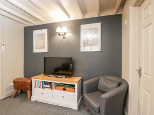 a living room with a chair and a tv at Paddock Cottage in Malmesbury