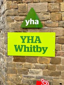 een teken op een stenen muur met de woorden: bij YHA Whitby in Whitby