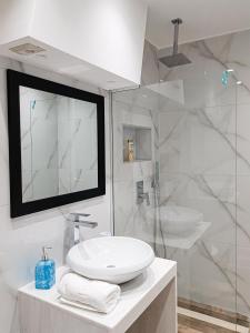 a white bathroom with a sink and a shower at Tirana Central Apartments - Premium in Tirana