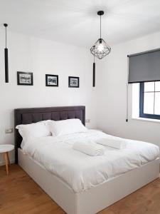 białe łóżko w białej sypialni z oknem w obiekcie Tirana Central Apartments - Premium w Tiranie