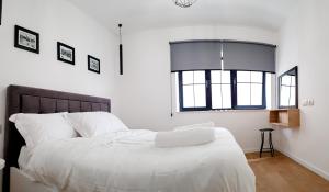 a bedroom with a bed with white sheets and a window at Tirana Central Apartments - Premium in Tirana