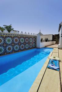 uma piscina com água azul e uma parede em Palais didi em Meknès