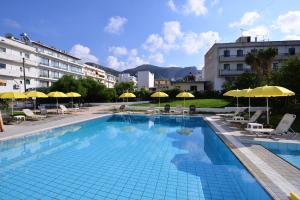 a swimming pool with chairs and umbrellas in a building at Arlen Beach Hotel in Hersonissos