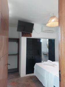 um quarto com uma cama e uma televisão de ecrã plano em Pousada Rocas Beach em Porto de Pedras