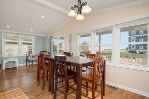 a dining room with a table and chairs and windows at This Is It by Oak Island Accommodations in Oak Island