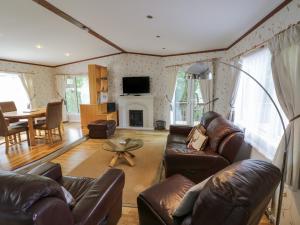 a living room with leather furniture and a fireplace at Foxglove in Leominster