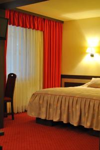 Schlafzimmer mit einem Bett und einem Fenster mit roten Vorhängen in der Unterkunft Hotel Dana in Amara