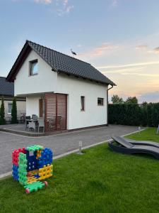 a small white house with a playground in the grass at Apartamenty Bursztynowe in Dębki