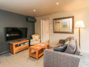 uma sala de estar com um sofá, uma televisão e uma mesa em Well Cottage em Malmesbury