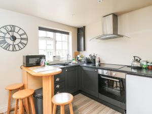 a kitchen with black cabinets and a table and stools at Well Cottage in Malmesbury