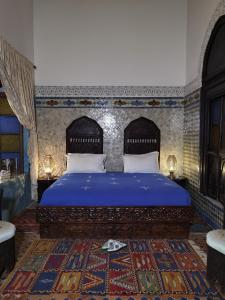 a bedroom with a king sized bed with blue sheets at Palais didi in Meknès