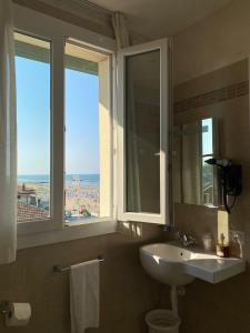 un bagno con lavandino e specchio e due finestre di Marina Beach Aparthotel a Rimini