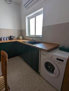 uma cozinha com uma máquina de lavar roupa e um lavatório em Fly Dodo Summer Residence em Marsaskala