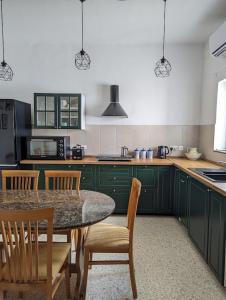 uma cozinha com armários verdes e uma mesa com cadeiras em Fly Dodo Summer Residence em Marsaskala