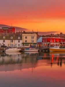 einen Sonnenuntergang über einem Hafen mit Booten im Wasser in der Unterkunft Admiralty House in Weymouth