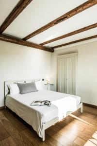 Habitación blanca con cama blanca y suelo de madera. en La Casa di Roby-2 studio la morra en La Morra
