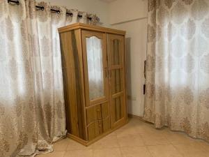 un armario de madera en una habitación con cortinas en One Bedroom Cozy Apartment- KNUST & free Parking, en Kumasi
