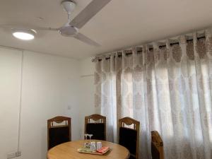 Zimmer mit einem Tisch, 2 Stühlen und einem Vorhang in der Unterkunft One Bedroom Cozy Apartment- KNUST & free Parking in Kumasi