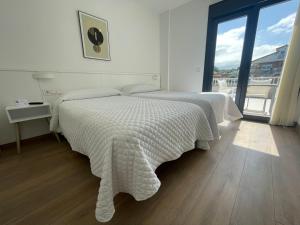 sypialnia z 2 łóżkami i dużym oknem w obiekcie Hostal montevideo w mieście Nigrán