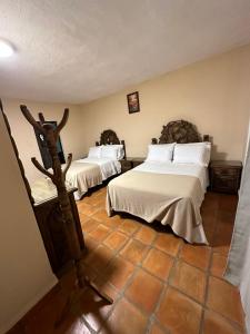 um quarto com 2 camas e piso em azulejo em Bebelines inn dos em San Miguel de Allende