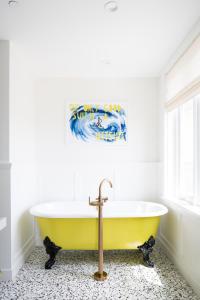 a yellow tub in a bathroom with a wave painting on the wall at Lido House, Autograph Collection in Newport Beach