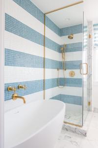 a bathroom with a tub and a shower with blue tiles at Lido House, Autograph Collection in Newport Beach