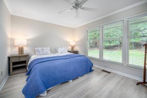 um quarto com uma cama azul e 2 janelas em The Cozy Cottage - 10 Min From UNC em Chapel Hill