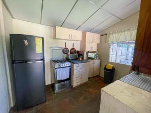 een keuken met een zwarte koelkast en een fornuis bij Casa De Playa El Encanto in El Porvenir