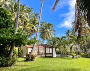 un jardin avec des palmiers et un petit bâtiment dans l'établissement Casa De Playa El Encanto, à El Porvenir