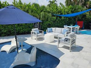 a patio with chairs and a table and an umbrella at Casa806 Men Only Guest House in Fort Lauderdale