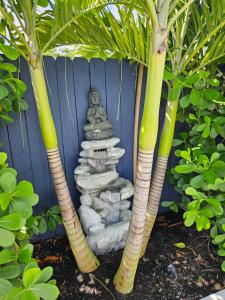 a zen garden with a stone statue between two trees at Casa806 Men Only Guest House in Fort Lauderdale