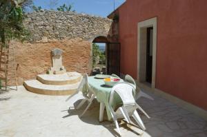 un tavolo e sedie su un patio con parete in pietra di Antico Casale Pizzo a Palazzolo Acreide