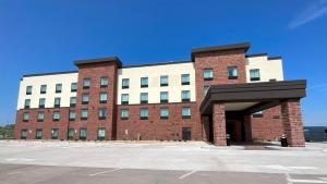 a large brick building with a parking lot in front at Cobblestone Hotel & Suites - Ottumwa in Ottumwa