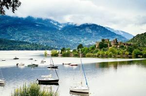 un grupo de barcos en un lago con un castillo en el fondo en Casa RuralRut en El Tiemblo, zona de baño natural muy cercana y a solo 50 min de Madrid en El Tiemblo