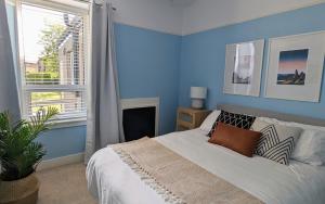 a blue bedroom with a bed and a window at Parkview Cottage - Lovely home overlooking park in Carnoustie