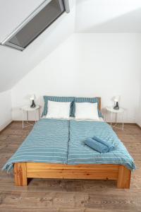 a bed with a blue comforter and two tables at Berkenyeliget Vendégház in Szigliget