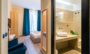 baño con lavabo y habitación con sofá en Musa Rooms Roma, en Roma