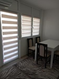 a dining room with a table and chairs and windows at Emir Apartman in Čapljina +3 photos
