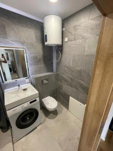 a bathroom with a toilet and a sink and a washing machine at Airport Apartment View Self Check-In Free parking in Vilnius