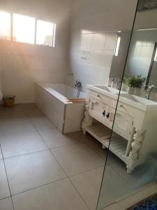 a bathroom with a tub and a sink and a mirror at Entire 4 bedroom house in Midrand, Johannesburg in Randjesfontein