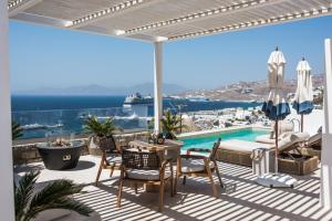 une terrasse avec une table et des chaises ainsi qu'une piscine dans l'établissement Νumi Boutique Hotel, à Mykonos