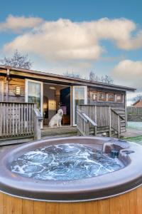 um cão sentado no deque de uma casa com uma banheira de hidromassagem em Ribblesdale Park em Gisburn