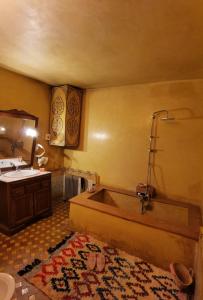 uma casa de banho com uma banheira, um lavatório e um tapete em Palais didi em Meknès
