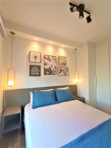 a bedroom with a large bed with blue pillows at Apartamento 1604 no Bosque com um quarto sala cozinha completa e uma vaga de garagem in Campinas