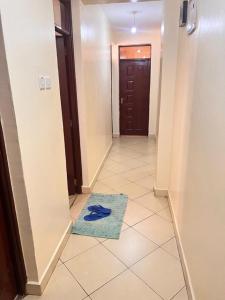 a hallway with a blue rug on a tile floor at J'Melot Adobas Apartment in Kisumu