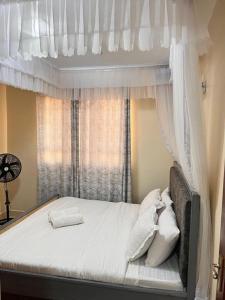 a bedroom with a canopy bed with a window at J'Melot Adobas Apartment in Kisumu