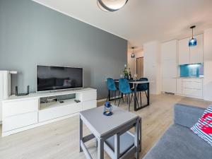 a living room with a couch and a tv and a table at Hello Apartments Letnica with private parking in Gdańsk